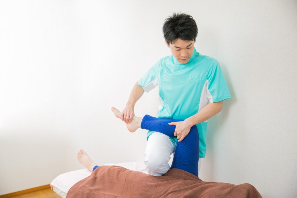 浜松の整体院松華で理学療法士の院長・平尾が、あおむけの方の膝を曲げて股関節を動かしている施術の様子